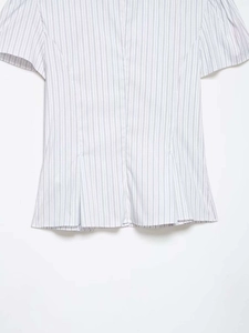Detail of blue striped poplin shirt showing peplum waist and crisp cotton fabric texture