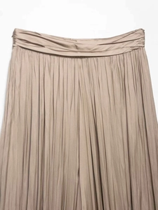 Detailweergave van geplooide satijnen broek in champagnekleur met een hoge tailleband