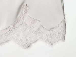 Detail of the asymmetrical hem with white floral lace trim on the silver satin skirt