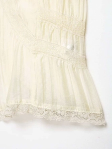 Close-up of semi-sheer fabric with delicate lace trim and pleat details on V-neck top