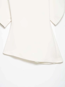 Detail of white off-shoulder shirt showing asymmetric hem and elegant bell sleeve texture