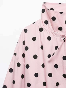 Detail of pink polka dot shirt with neck tie design and high-quality fabric texture