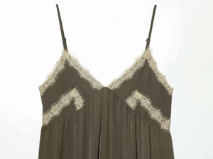 Detailed view of the olive green V-neck dress with intricate cream lace trim and pleats