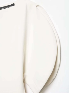 Detail of white puff sleeve shirt featuring a woven brand neck label and premium fabric