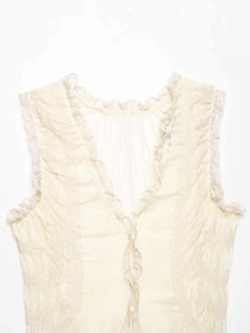 Detailed macro view of the V-neckline with delicate lace trim on the beige sleeveless top