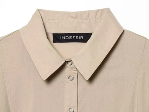 Close-up detail of silver metal snap buttons and collar on khaki short sleeve dress