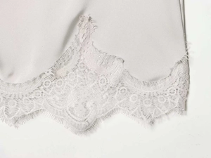 Detailed close-up of grey satin fabric with delicate white eyelash lace trimming edge