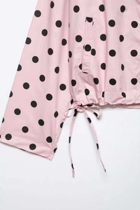 Detail of pink polka dot jacket showing side pocket and adjustable drawstring hemline