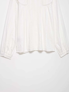 Close-up of white cotton lace stitching and vertical striped texture on long sleeve shirt