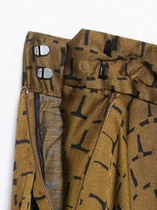 Macro shot of snakeskin patterned trousers showing hook-and-bar closure and zipper