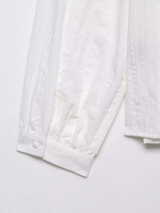 Close-up of white lace blouse cuff featuring textured fabric and tonal button detail