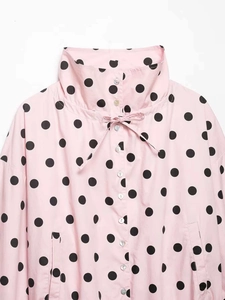 Detail of pink polka dot jacket showing stand collar, drawstring, and pearl buttons