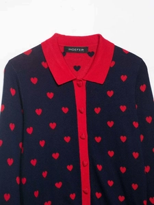 Detailed view of heart pattern knit cardigan with navy blue base and red collar trim