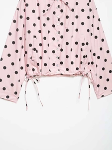 Detail of pink polka dot shirt with button-down front, side pockets and drawstring hem