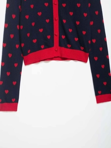 Detail of navy knit cardigan with red heart patterns and matching red heart-shaped buttons