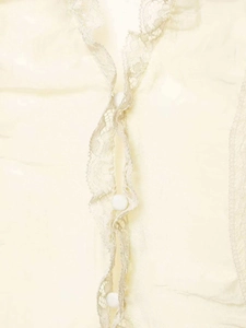Macro detail of the light yellow sleeveless blouse with delicate lace edges and cloth buttons