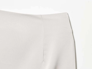 Close-up of the waistband and side seam details on a light grey lace mini skirt