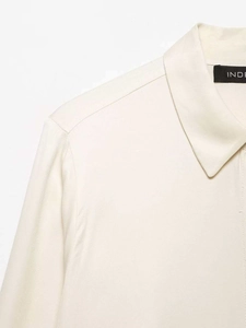 Detailed close-up of cream satin shirt collar stitching and brand label craftsmanship