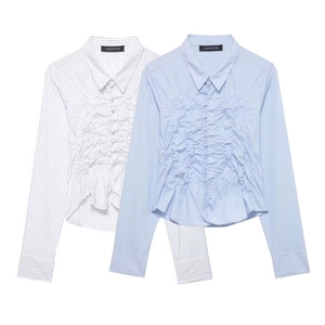 Women's light blue long sleeve shirt with ruched details and asymmetrical ruffled hemline