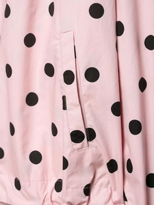 Detail of pink jacket showing black polka dot print and reinforced pocket stitching