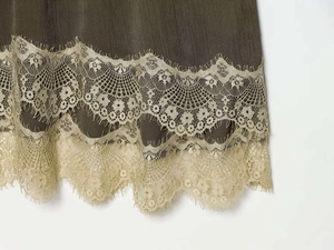 Detail of olive green ribbed fabric hem featuring exquisite champagne gold floral lace trim