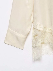 Detailed close-up of silk satin sleeve and delicate eyelash lace hem on beige blouse