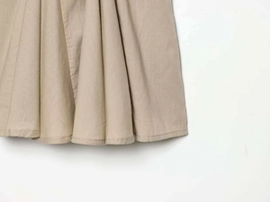 Detailed close-up of khaki summer dress hem showing fine stitching and pleated cotton texture