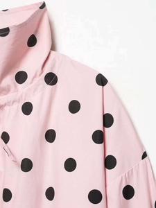 Detail of pink polka dot fabric with high collar and drop shoulder seam design
