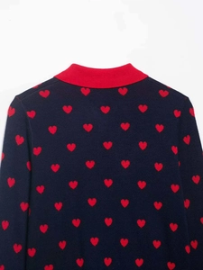 Close-up of navy blue knit cardigan featuring red heart patterns and ribbed collar