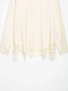 Close-up of silk-like cream blouse featuring delicate lace hem and smooth texture