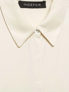Detailed macro shot of cream satin shirt collar with iridescent pearl button and texture
