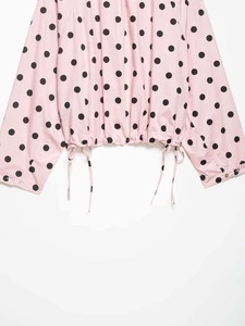 Detail of pink polka dot jacket with adjustable drawstring hem and buttoned cuffs
