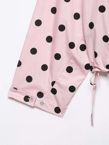Detailed close-up of pink polka dot blouse cuffs with white buttons and side drawstrings