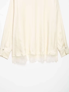 Detail view of cream satin shirt featuring exquisite lace hem and silky fabric texture