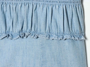 Close-up of smocked light blue short sleeve shirt with delicate ruffle hem detail