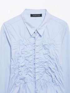 Detail view of light blue shirt showing vertical ruching texture and button closure