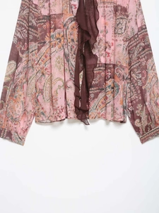 Détail d'un chemisier en mousseline à imprimé paisley avec volants et boutons roses