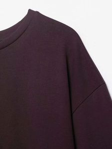 Dettaglio del girocollo a coste e della spalla scesa sulla felpa color bordeaux scuro