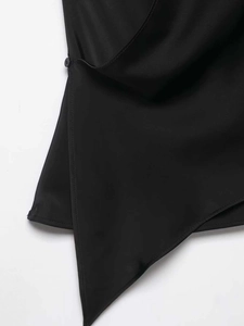 Détail de l'ourlet asymétrique croisé avec bouton noir sur un haut élégant à col en V