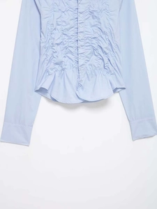 Detailed view of light blue shirt featuring ruffled pleats and button-down front texture