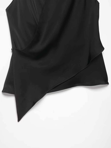 Détail du gilet portefeuille en satin noir avec bouton latéral et ourlet irrégulier