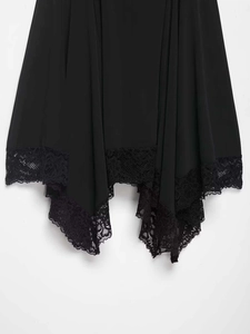 Détail d'une robe noire avec ourlet mouchoir irrégulier et bordure en dentelle florale