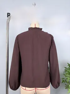Detail view of brown chiffon blouse featuring a ruffled stand collar and lantern sleeves