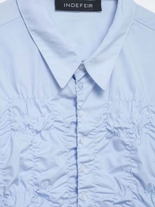 Close-up of light blue ruched shirt showing pointed collar and tonal buttons detail
