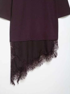 Dettaglio di maglia bordeaux con pizzo raffinato e bordo asimmetrico sulla parte superiore