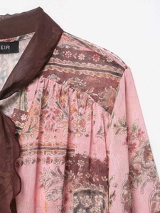 Détail de chemisier en mousseline à motif paisley rose et col marron avec liens à nouer