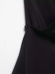 Détail d'un haut noir sans manches à col en V avec un bouton rond et des coutures nettes