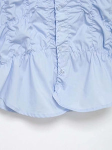 Detailed view of light blue smocked fabric with center buttons and ruffled hem