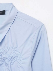 Close-up detail of light blue shirt featuring a classic collar and elegant shirring design