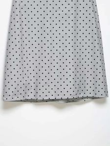 Détail du tissu gris clair à pois noirs avec des finitions de couture sur l'ourlet